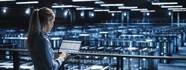 Female IT engineer uses laptop computer in a hosting provider’s server room