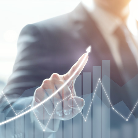 Orang dengan setelan jas sedang menggambar kurva arah ke atas pada grafik garis