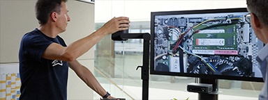 2 engineers in the office checking a motherboard with a magnifier on a monitor with Kingston memory installed