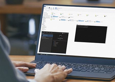 a hand typing on a laptop keyboard on a desk with a cmd command on the screen