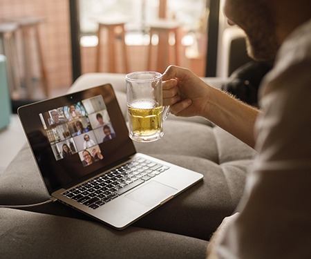Người dùng máy tính xách tay trong cuộc trò chuyện video đang cầm một cốc bia