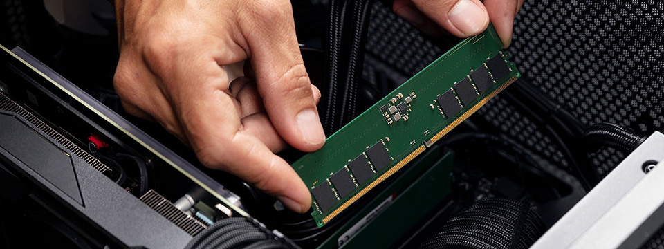 Che cos'è l'AEMP? Mani che tengono un modulo di memoria Kingston ValueRAM DDR5 all'interno della scheda madre, in procinto di installare il modulo.
