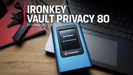 컴퓨터 책상 위에 놓인 노트북에 Kingston IronKey Vault Privacy 80 외장 SSD가 놓여 있습니다.