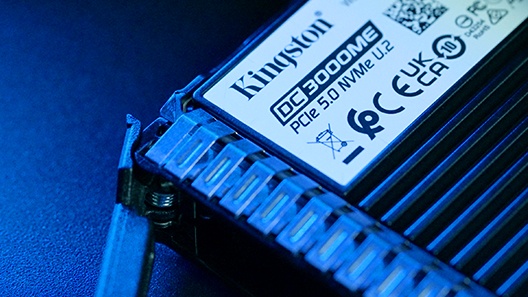 Tampilan jarak dekat tangan seseorang memasukkan SSD Kingston DC ke dalam rak server